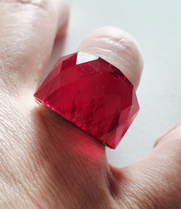 Anel dourado, em aço, com vermelho facetado na parte de cima. T17