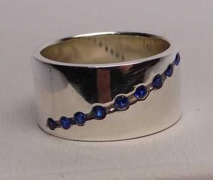 Szeroka srebrna obrączka  niebieskie kamienie R.14.  1 cm.