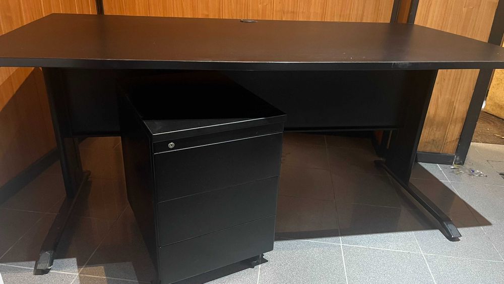 Secretária preta e modulo de gavetas.