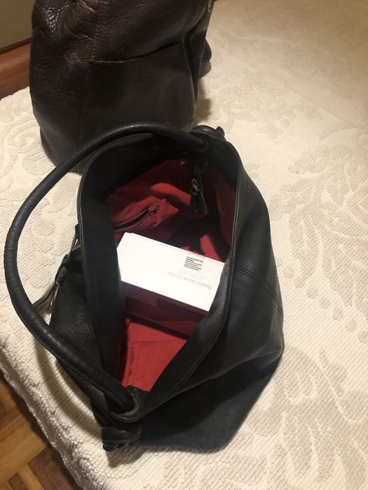 Mochila em pele castanha e bolsa preta . Ambas em pele