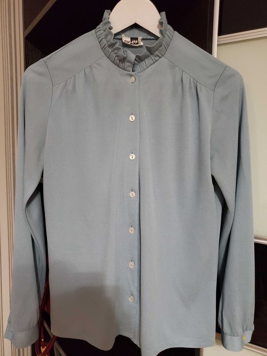 Вінтажна світло-блакитна блузка з рюшами та ґудзиком.