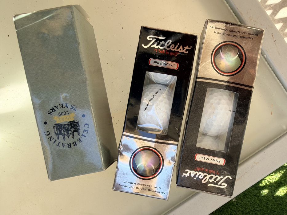 Bolas de golfe novas nas caixas e de treino