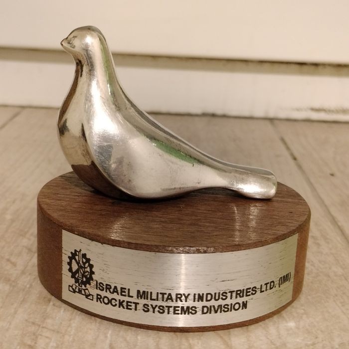 srebrna figurka ptaka (symbolu pokoju) na drewnianym stojaku