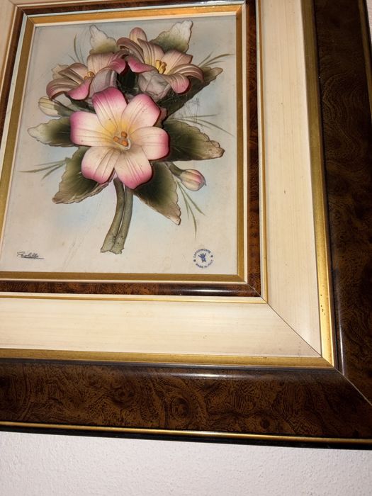 quadro decorativo com uma pintura floral em estilo clássico, protegido por vidro e emoldurado em madeira. Capodimonte