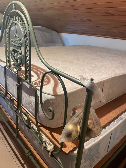 Cama de casal em ferro com colchão e estrado.