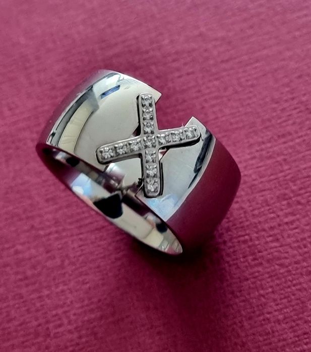 Anel grosso prateado, em aço, com um X em zirconias. T20