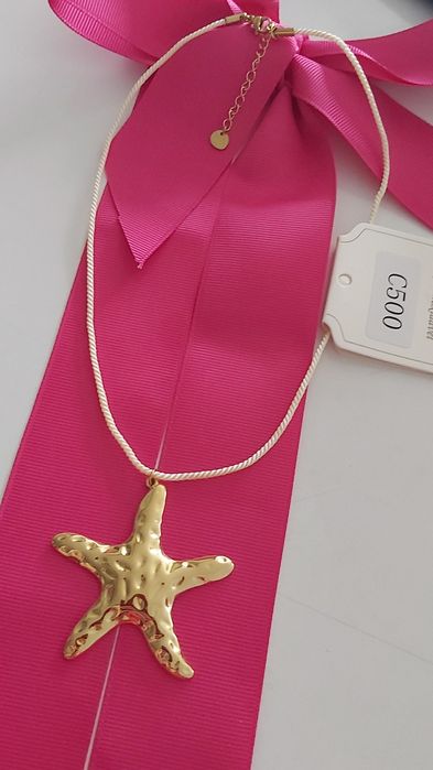 Colar dourado, em aço, com pingente em forma de estrela. Tem extensor