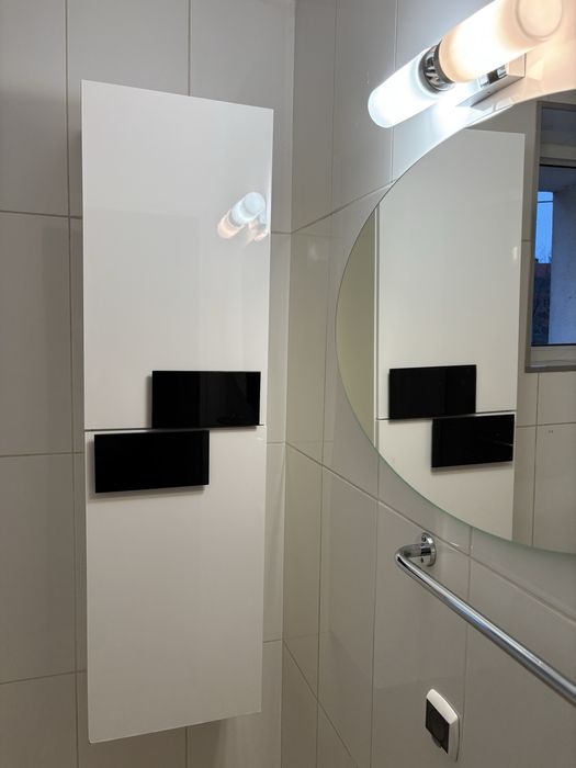 Biała pionowa szafka łazienkowa z czarnymi elementami i półkami