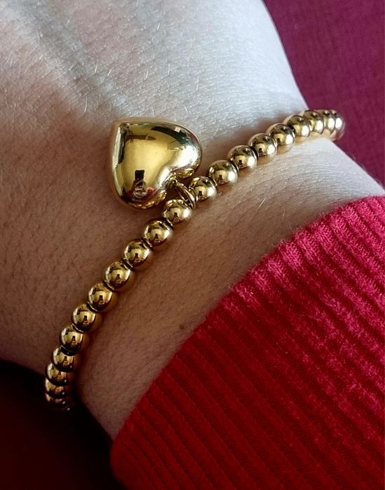 Pulseira dourada, em aço, toda às bolinhas e com 1 coração. Tem extens