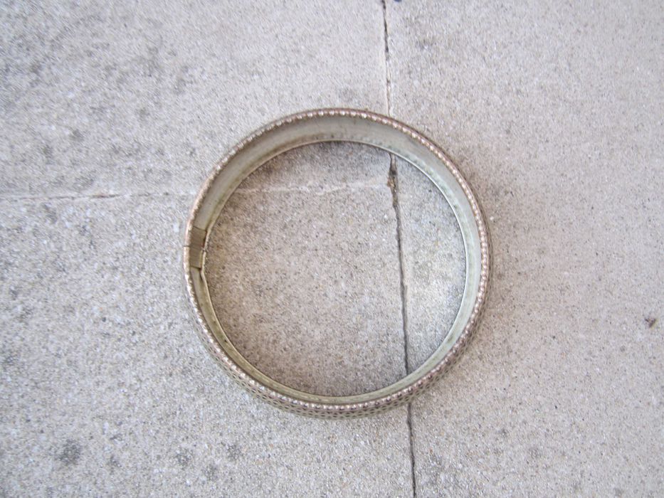 Pulseira rígida prateada com intrincado padrão geométrico triangular perfurado