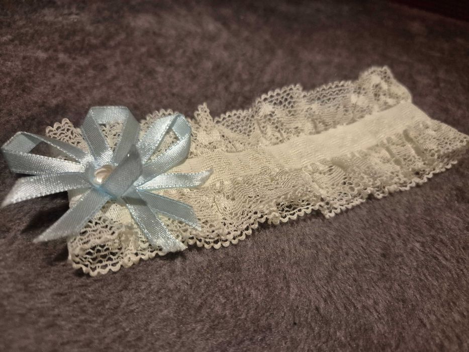 Podwiązka ślubna z koronki, ozdobiona błękitną kokardką