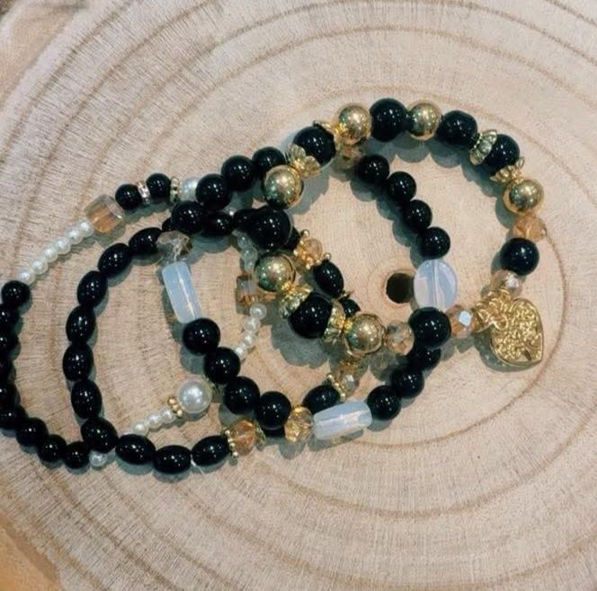 Conjunto de 4 pulseiras elásticas em tons de preto e dourado.