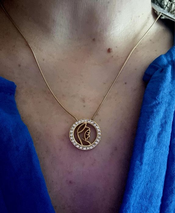 Colar dourado, em aço, com pingente da Nossa Senhora rodeada de zirconias.