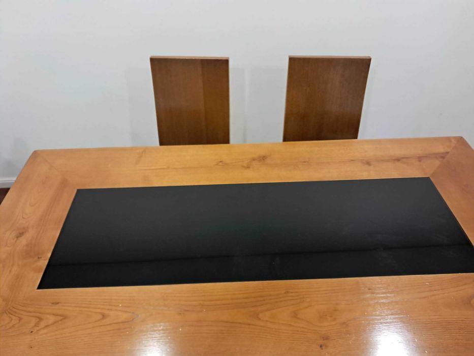 Mesa madeira, com tampo parcial em vidro preto e 6 cadeiras com assento em pele. Oferta móvel a condizer