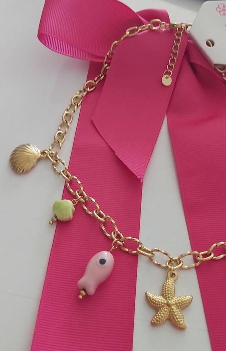 Colar dourado, em aço, com 7 pingentes diferentes. Tem extensor