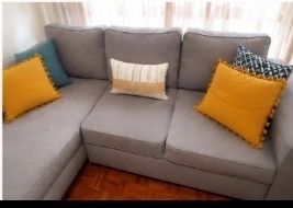 Sofá chaise longue em tecido cinzento, usado mas em bom estado geral.