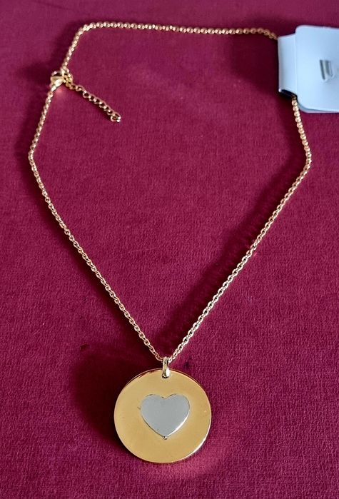 Colar dourado, em aço, com pingente redondo dourado e um coração prateado no centro