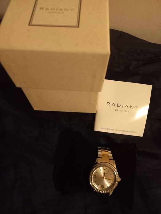 Relógio prateado e dourado com zirconias à volta do mostrador.