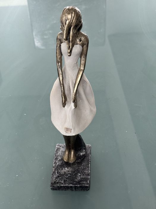 Peça decorativs em formato de mulher com o cabelo a fugir com o vento.