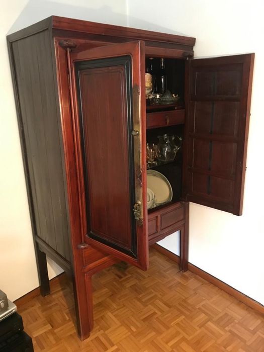 Armário de madeira avermelhada estilo oriental com portas e gavetas