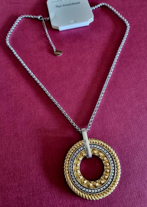 Colar prateado, em aço, com pingente bicolor. Tem extensor