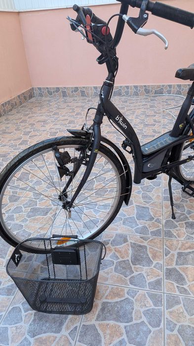 bicicleta  B'Twin Elops, apresentando um quadro de design urbano em preto.Modelo: B'Twin Elops 3 ou Elops 300. Inclui guarda-lamas e um selim preto.