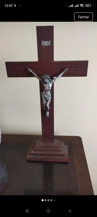Crucifixo de mesa composto por uma cruz de madeira escura com uma base escalonada de vários níveis.A figura tridimensional do corpo de Cristo (corpus)