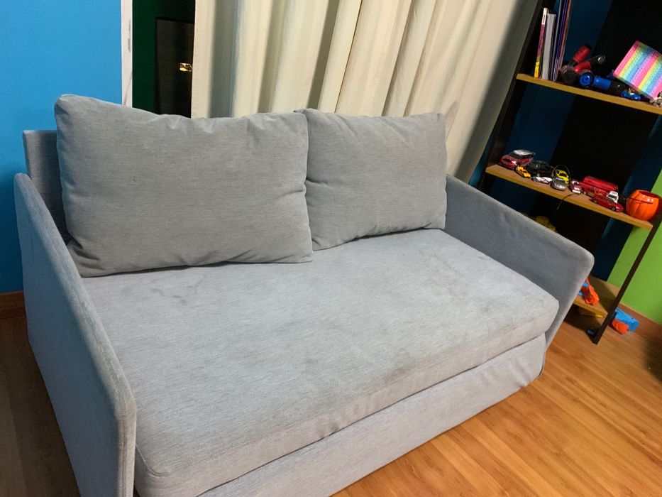 Sofá cama cinza com uma pequena quemadura