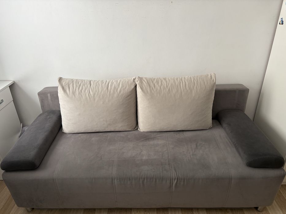 szara rozkladana sofa z poduszkami