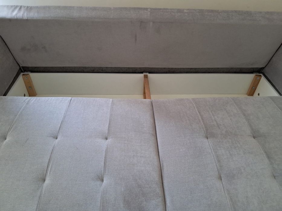 Szara sofa rozkładana z pojemnikiem na pościel