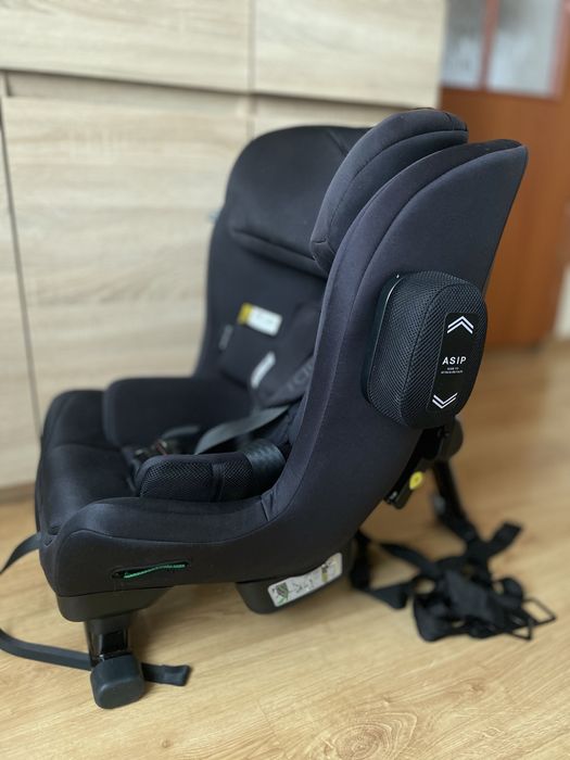 Czarny fotelik samochodowy axkid minikid tylem na pasy