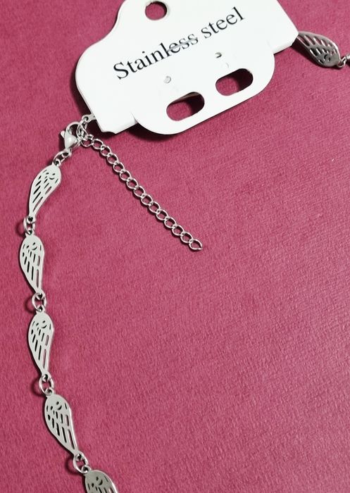 Conjunto prateado (colar e pulseira), em aço,  com asas de anjo.