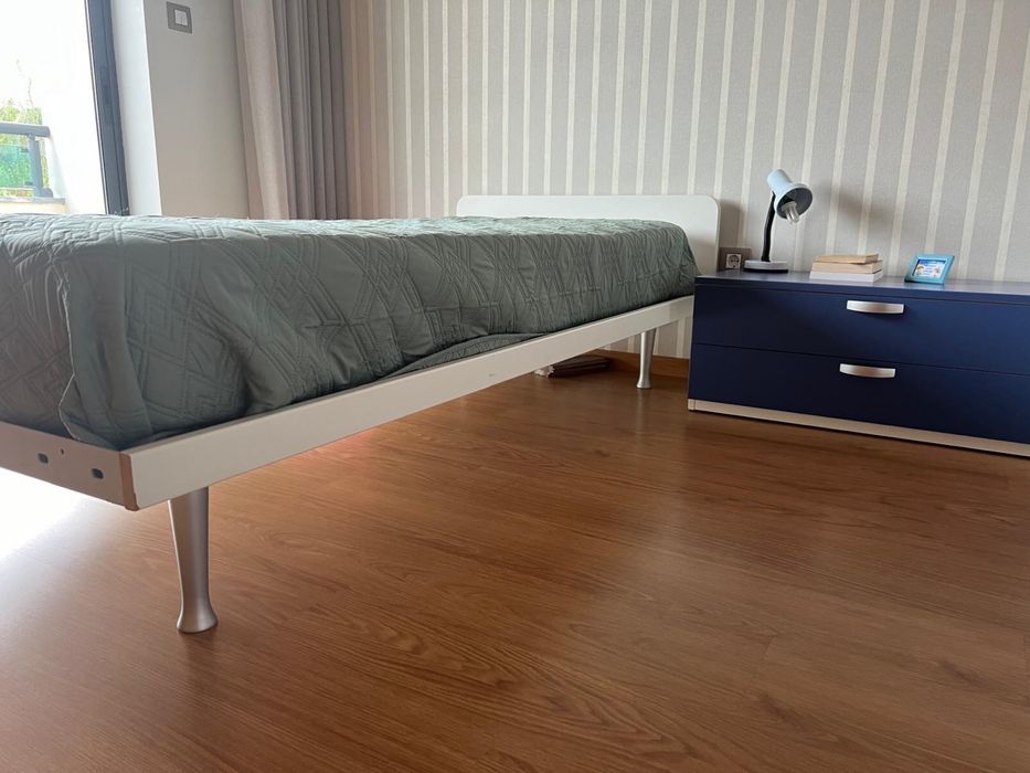 Quarto com cama , mesa de cabeceira e secretaria com estante