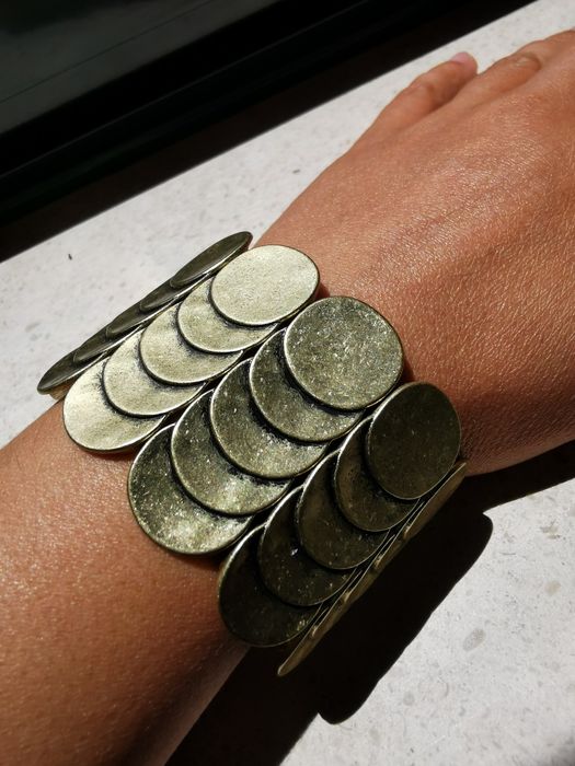 Pulseira em metal dourada, ajustável ao pulso