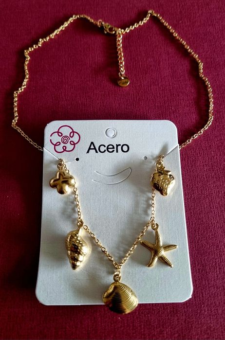 Colar dourado, em aço, com 5 pingentes diferentes. Tem extensor.