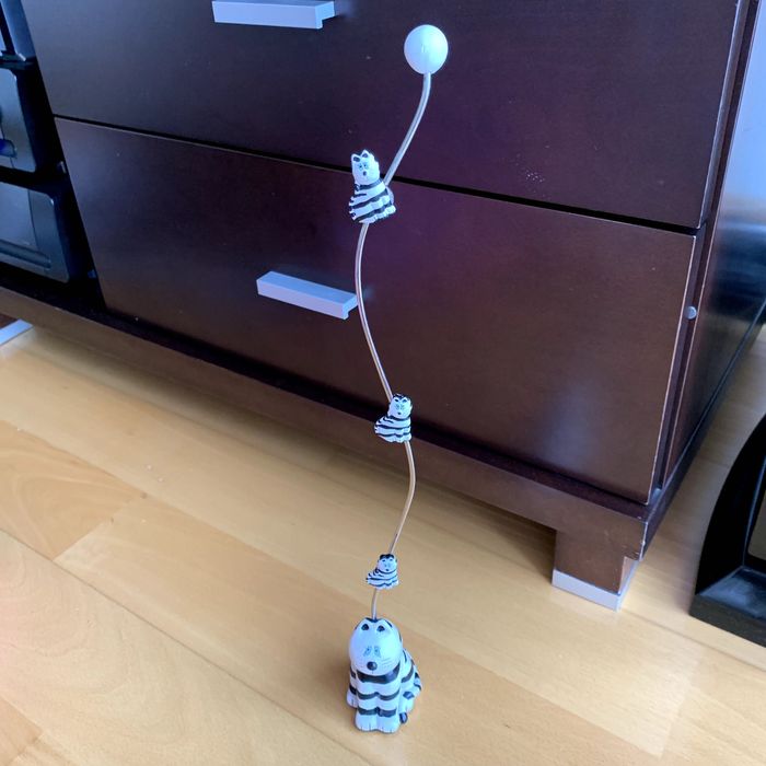 Pisa-papéis com aste vertical e três suportes magnéticos (gatos).