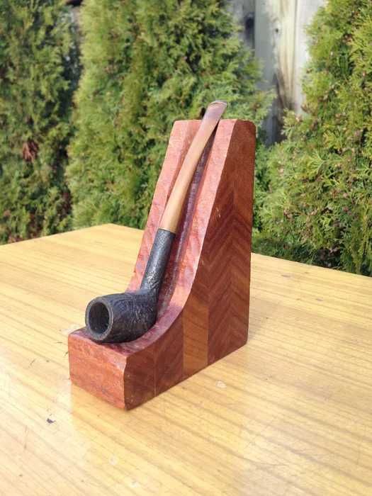 Fajka do tytoniu w drewnianym stojaku.