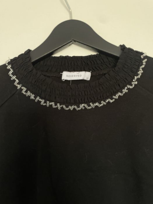 Dzianinowa sukienka z ozdobą przy dekolcie.