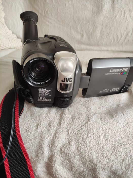 câmara de vídeo digital/analógica vintage JVC Compact VHS-C  GR-AXM300U ou similar), com um ecrã LCD articulado e visor ocular.