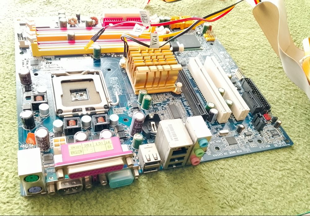 Płyta główna Gigabyte wraz z procesorem Intel Celeron głośniczkiem i kablami.