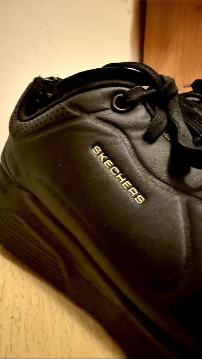 Klasyczne, w pełni czarne sneakersy marki Skechers ze złotymi detalami