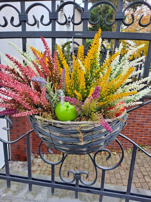 Wrzosy sztuczne w koszyku na ogrodzenie.
