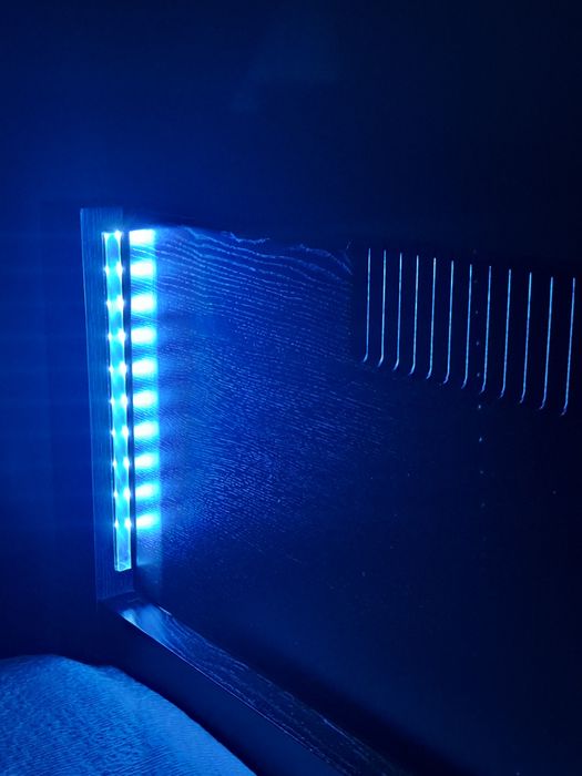 Cama de casal,  cor castanho escuro, com iluminação.