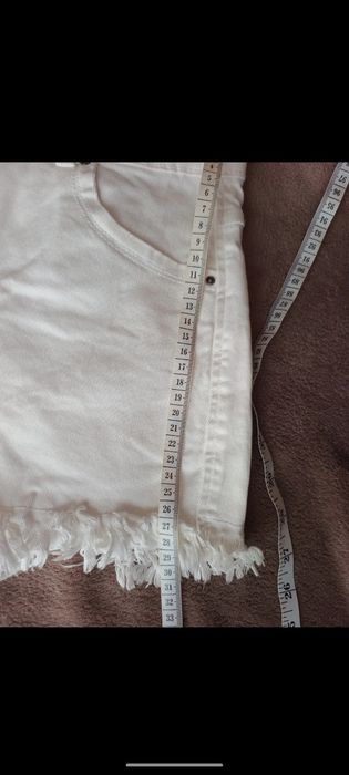 Białe strzępione spodenki