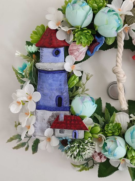 Guirlanda artesanal marítima com flores, conchas e farol decorativo