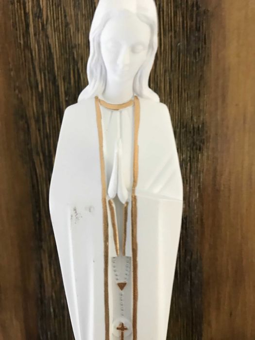 Estatueta da Virgem Maria em uma prateleira de madeira