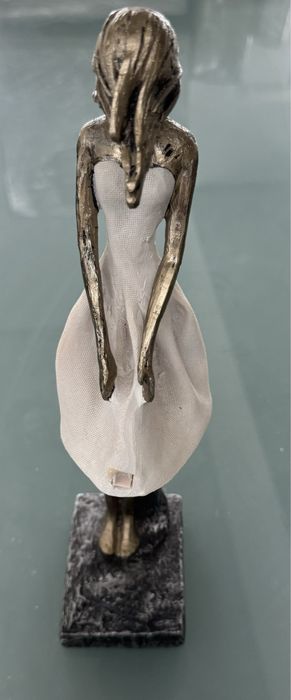 Peça decorativs em formato de mulher com o cabelo a fugir com o vento.
