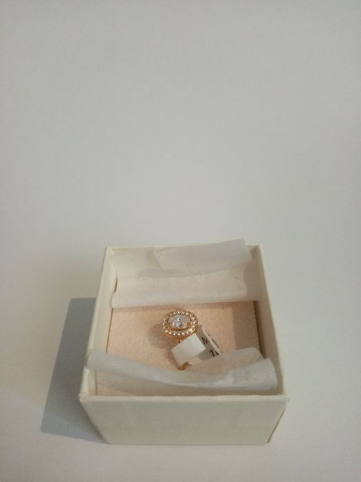 Anel dourado com pequenos cristais a rodear um cristal grande.