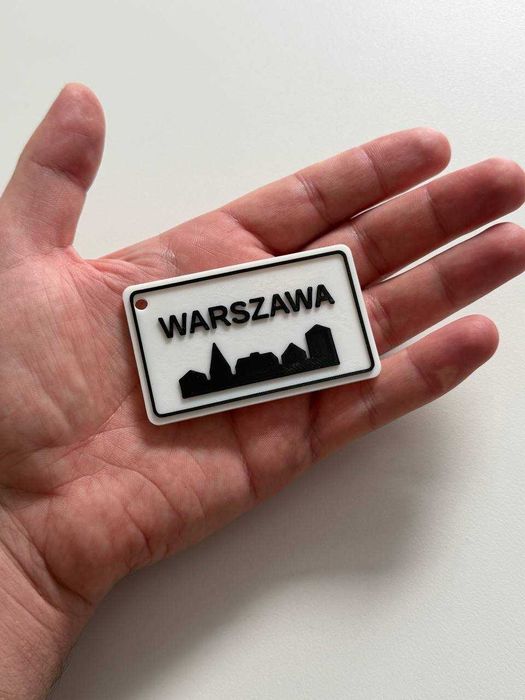 Brelok Warszawa w formie znaku drogowego.