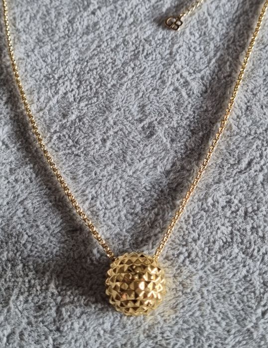 Colar dourado, em aço, com meia bola toda trabalhada. Tem extensor